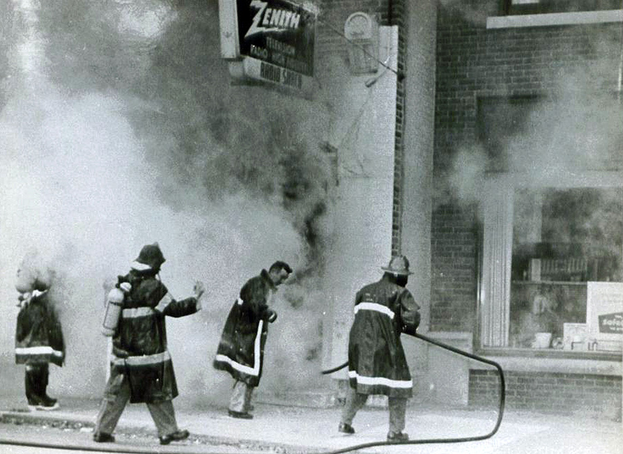 black and white photo of firefighters putting out a fire
