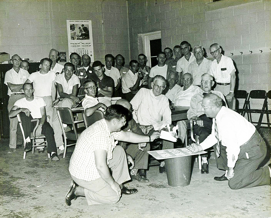 black and white photo of men burning a piece of paper