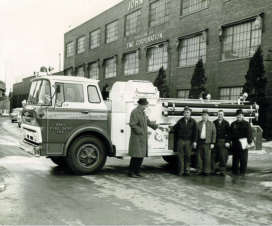 black and white photo of men standing in front of a firetruck